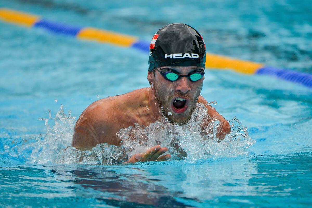 Andreas Onea beim Schwimmen mit Bademütze und Schwimmbrille auf der Schwimmbahn, den Kopf über Wasser