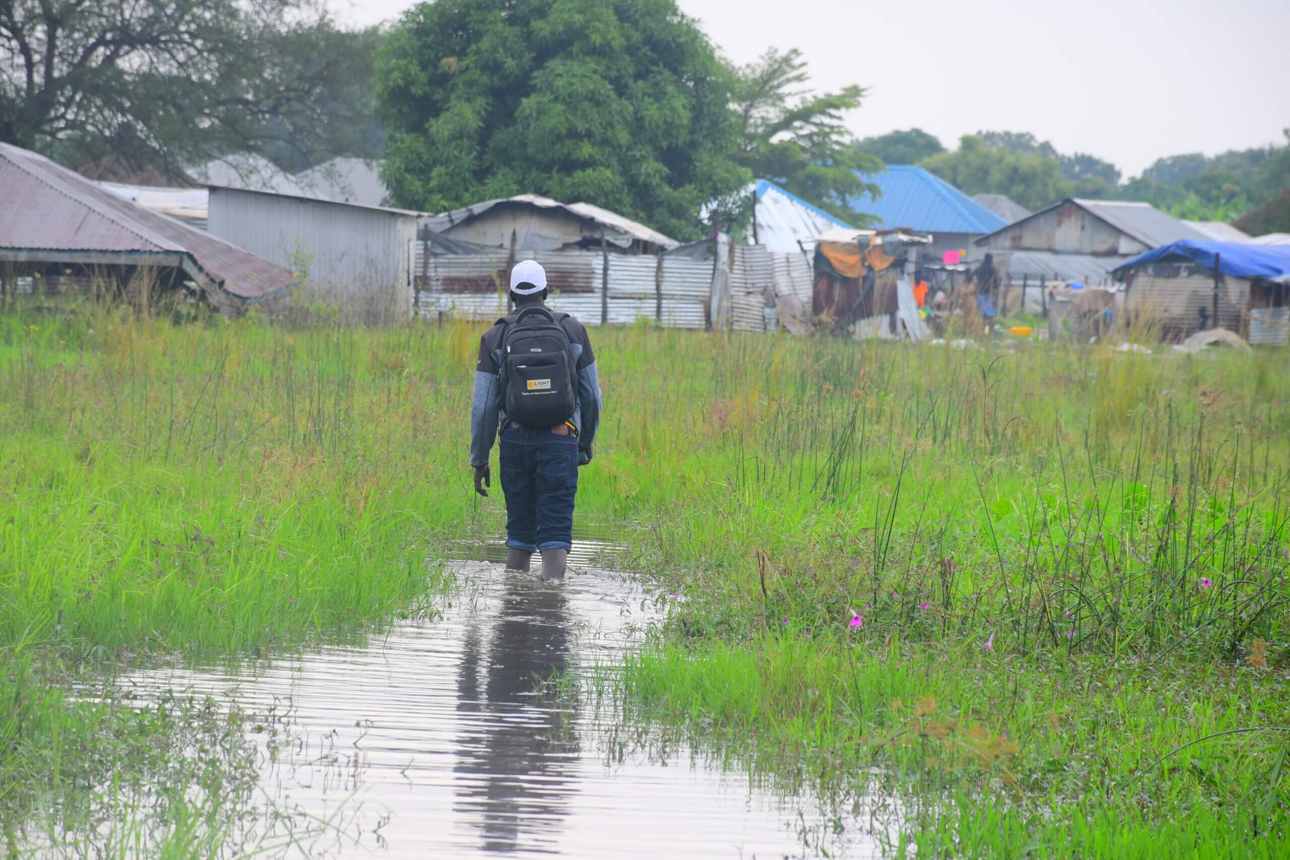 Ein Mann stapft durch eine überflutete Wiese nahe eines Camps für Geflüchtete im Südsudan.