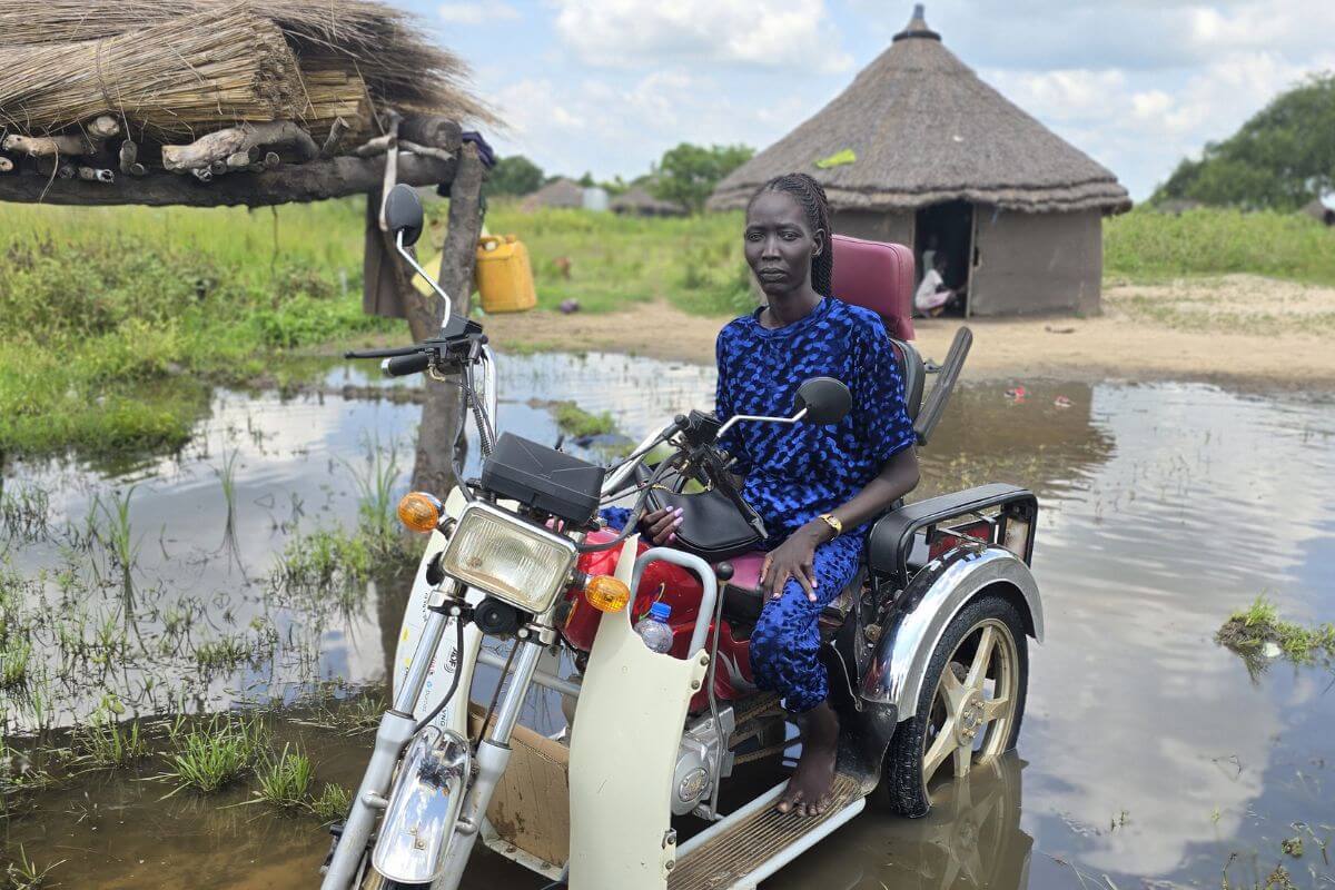 Inklusionsberaterin Amer Ajith auf einem motorisierten Roller in einem überfluteten Gebiet im Südsudan