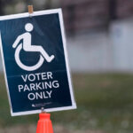 A blue sign with white words reading “Voter parking only” and a white symbol of a wheelchair user. The sign is from an election in Minnesota, United States.