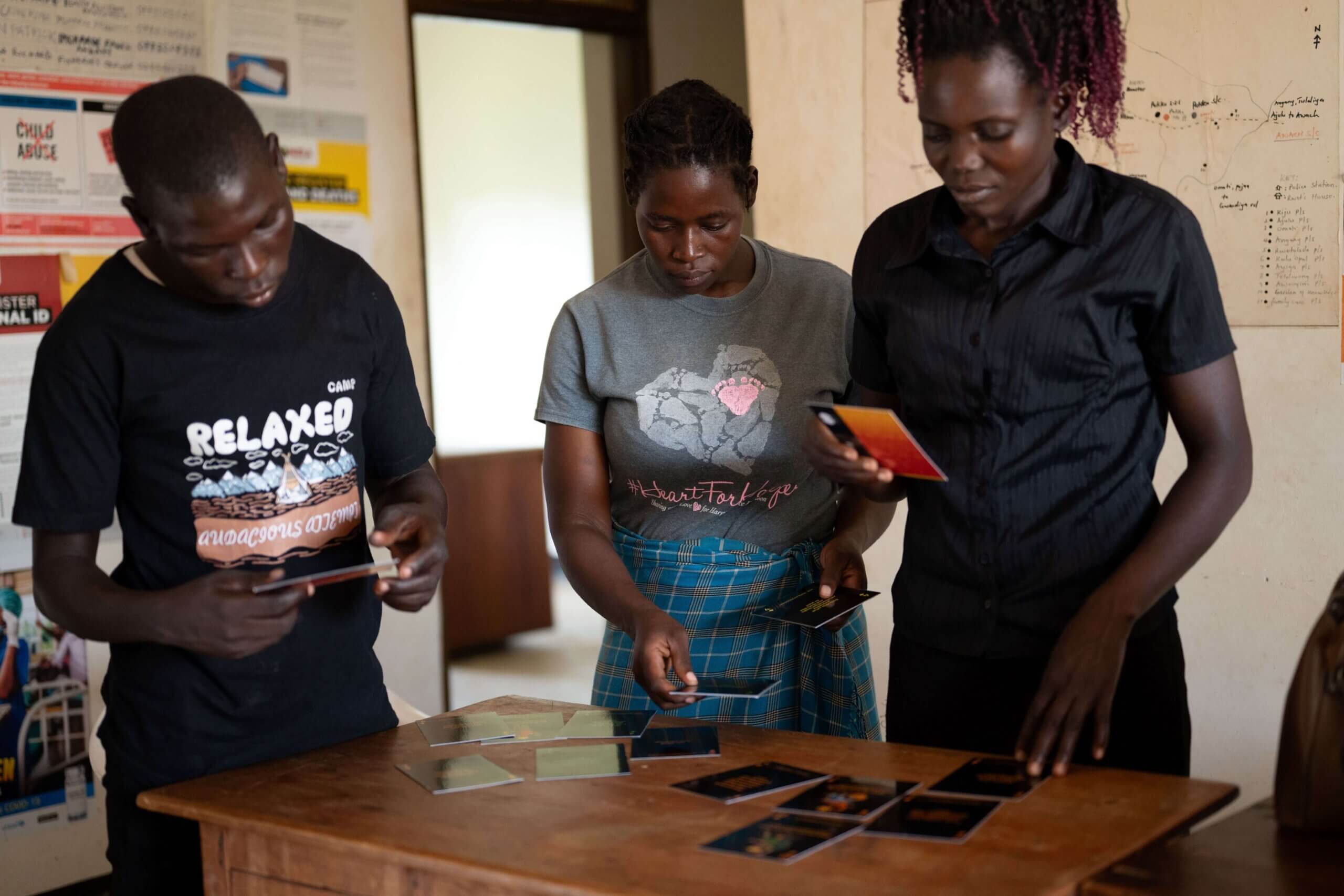 Three women project participants play a self-discovery card game in Uganda.