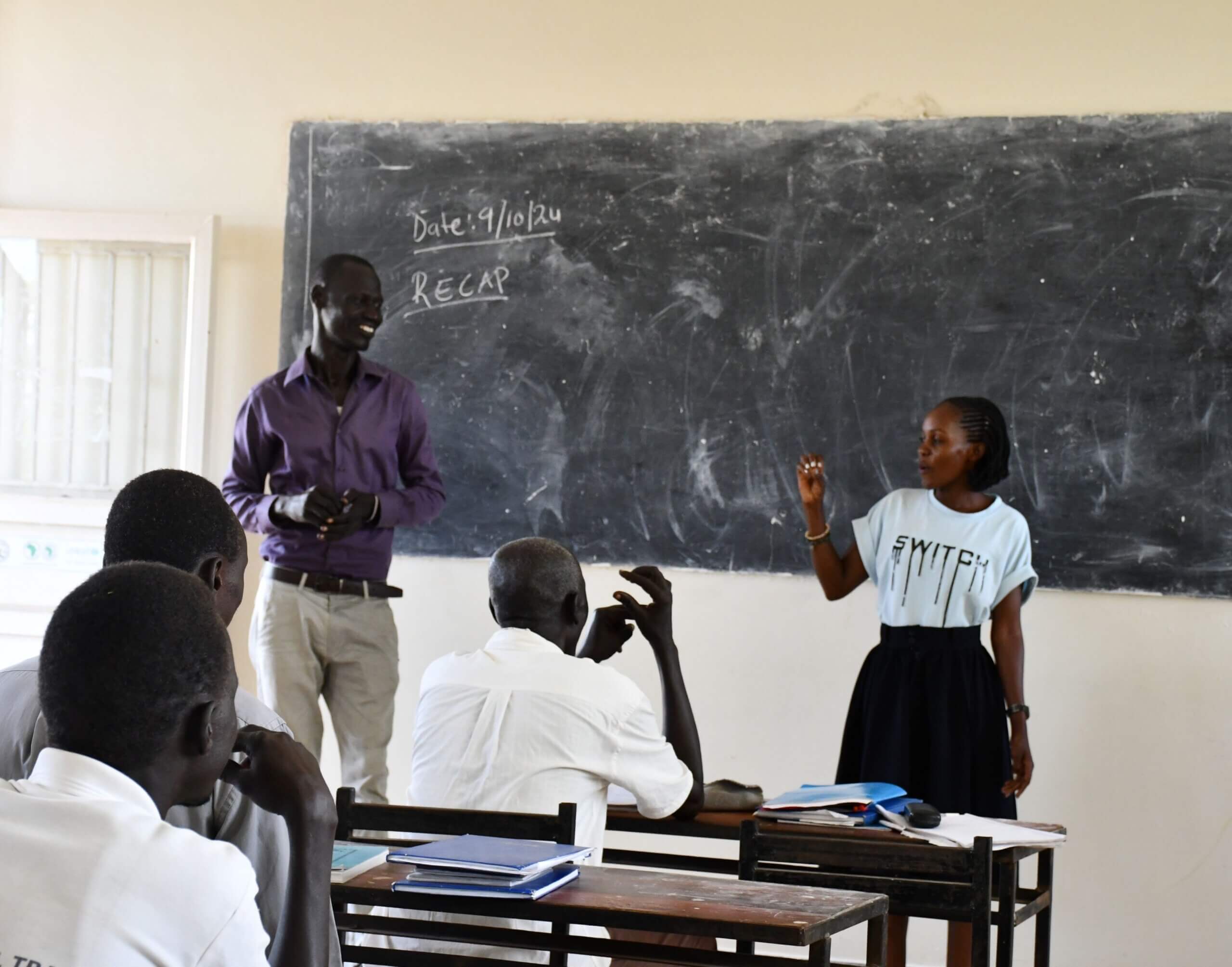 Beatrice, a teacher practising signs in front of a blackboard in her class at RNTTI.