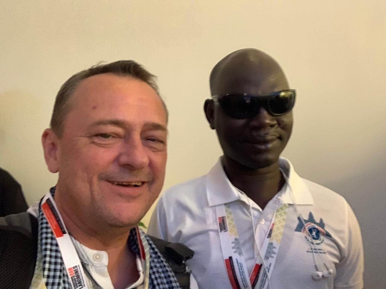 Issa pictured on the right at the conference with  David Curtis, Disability Inclusion Advisor at Light for the World. Issa is wearing a white shirt and dark sunglasses.